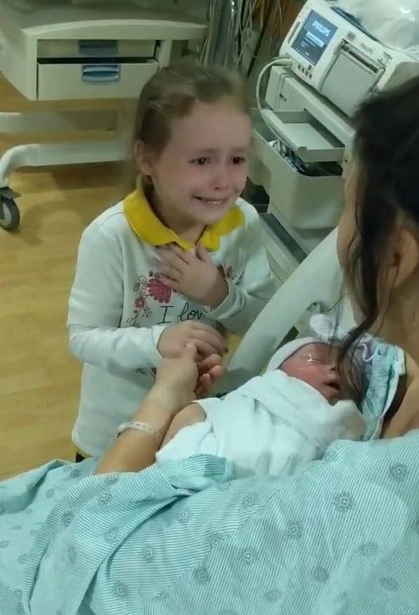 Una bambina non trattiene le lacrime di gioia quando vede la sorellina appena nata.